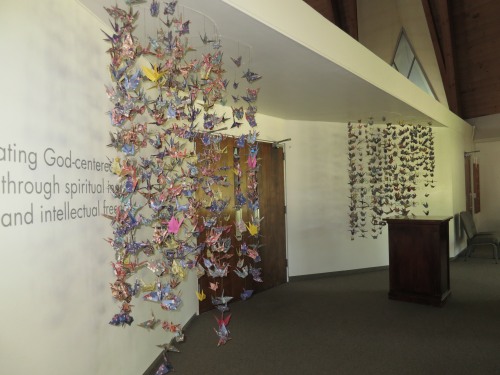 Church interior (foyer) with a display of many colorful origami cranes hanging from the ceiling